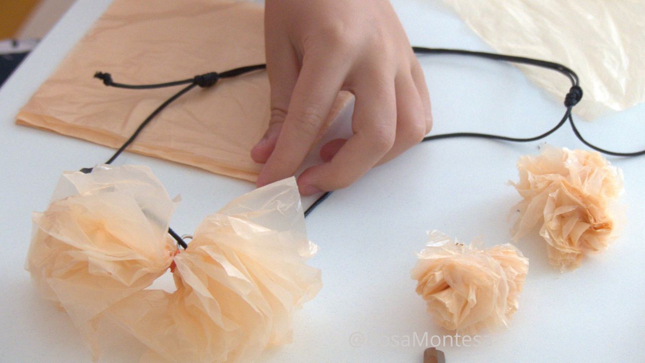 Manos de una niña en el taller de bisutería reciclando bolsas de plástico